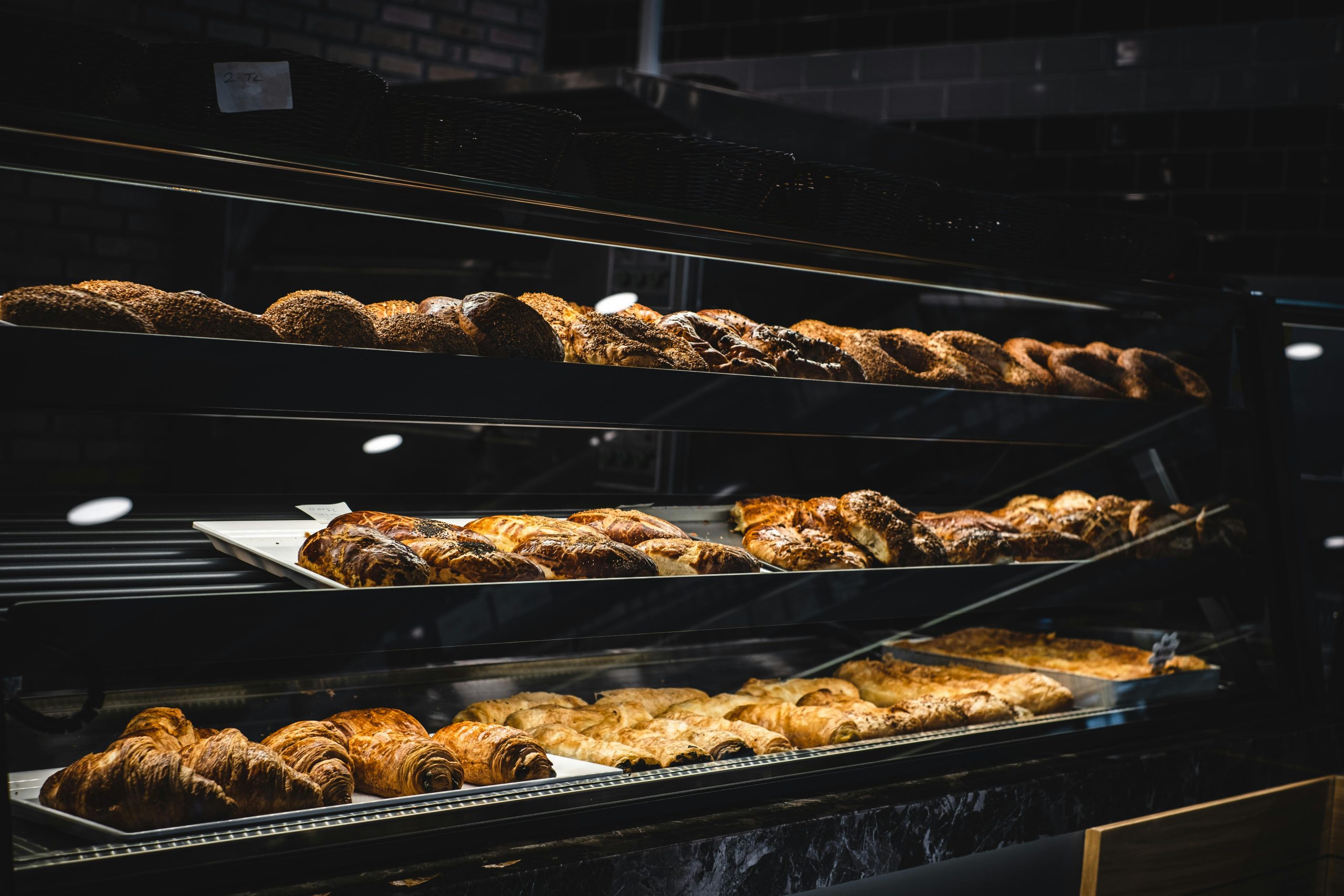 A variety of freshly baked pastries and breads in a glass display case at a bakery.